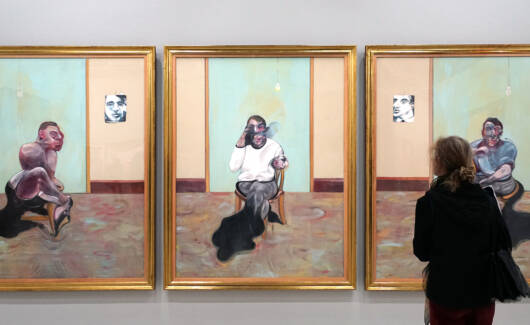 Een bezoeker die kijkt naar de triptiek Drie studies voor een portret van Lucian Freud van Francis Bacon.