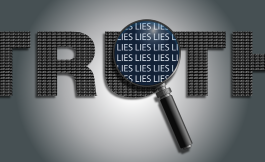door een loep zie je de woorden 'lies' in het woord 'truth'